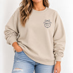 Woman wearing the Raised Better Than This crest crewneck sweatshirt in Sand with a navy left-chest crest