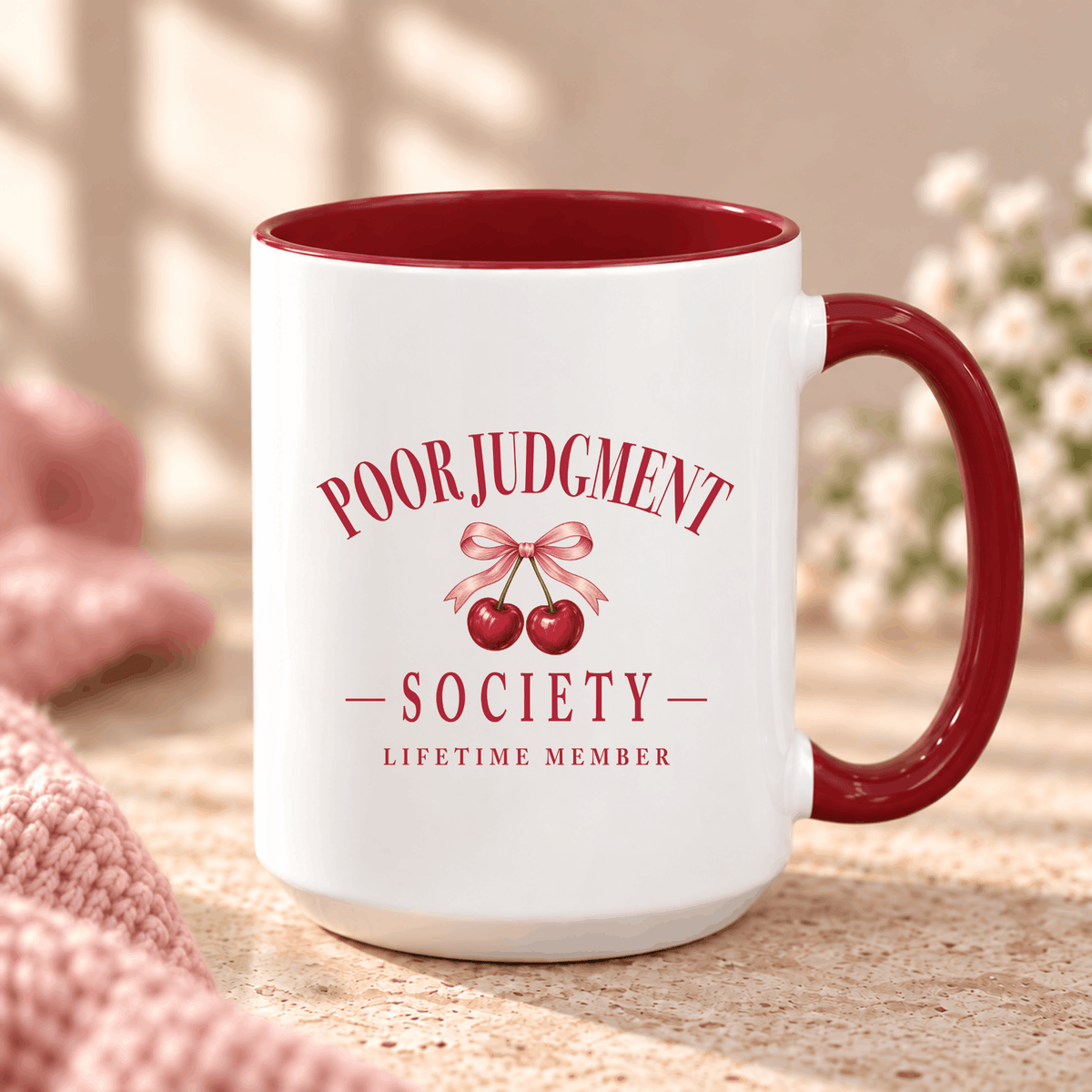Poor Judgment Society Lifetime Member mug in Maroon on a marble counter with pink knit and flowers