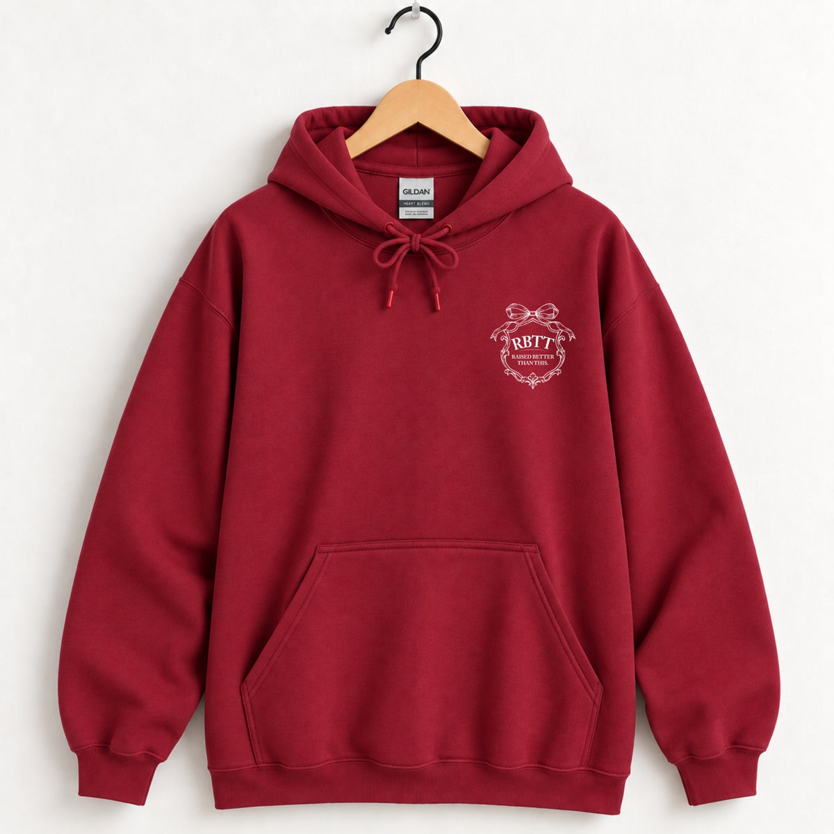 Raised Better Than This crest hoodie in Cardinal Red on a wooden hanger