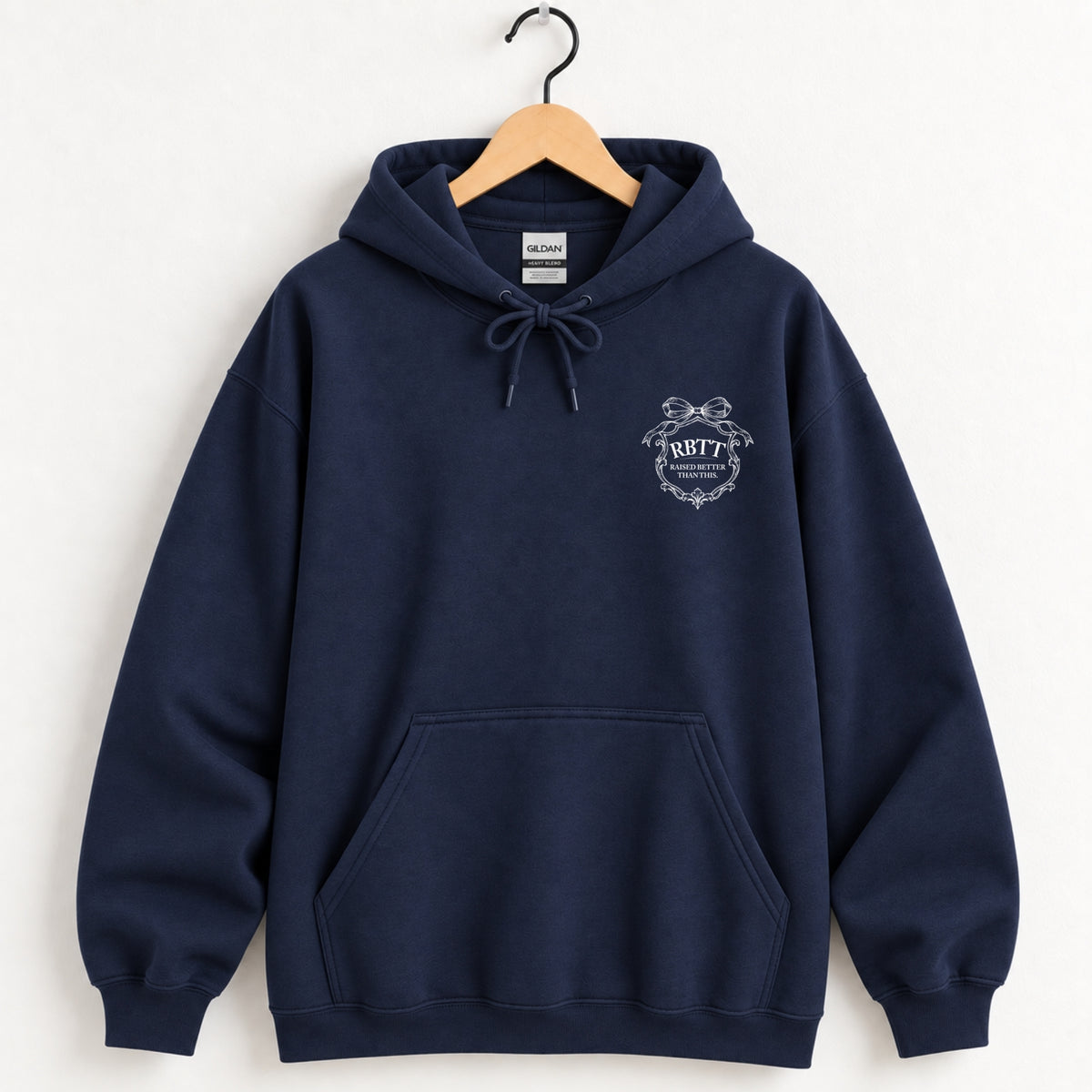 Raised Better Than This crest hoodie in Navy on a wooden hanger, white left-chest crest