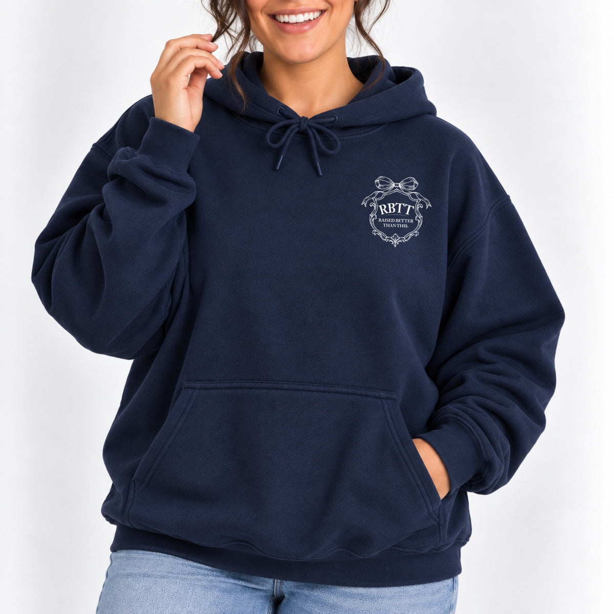 Woman wearing the Raised Better Than This crest hoodie in Navy with jeans