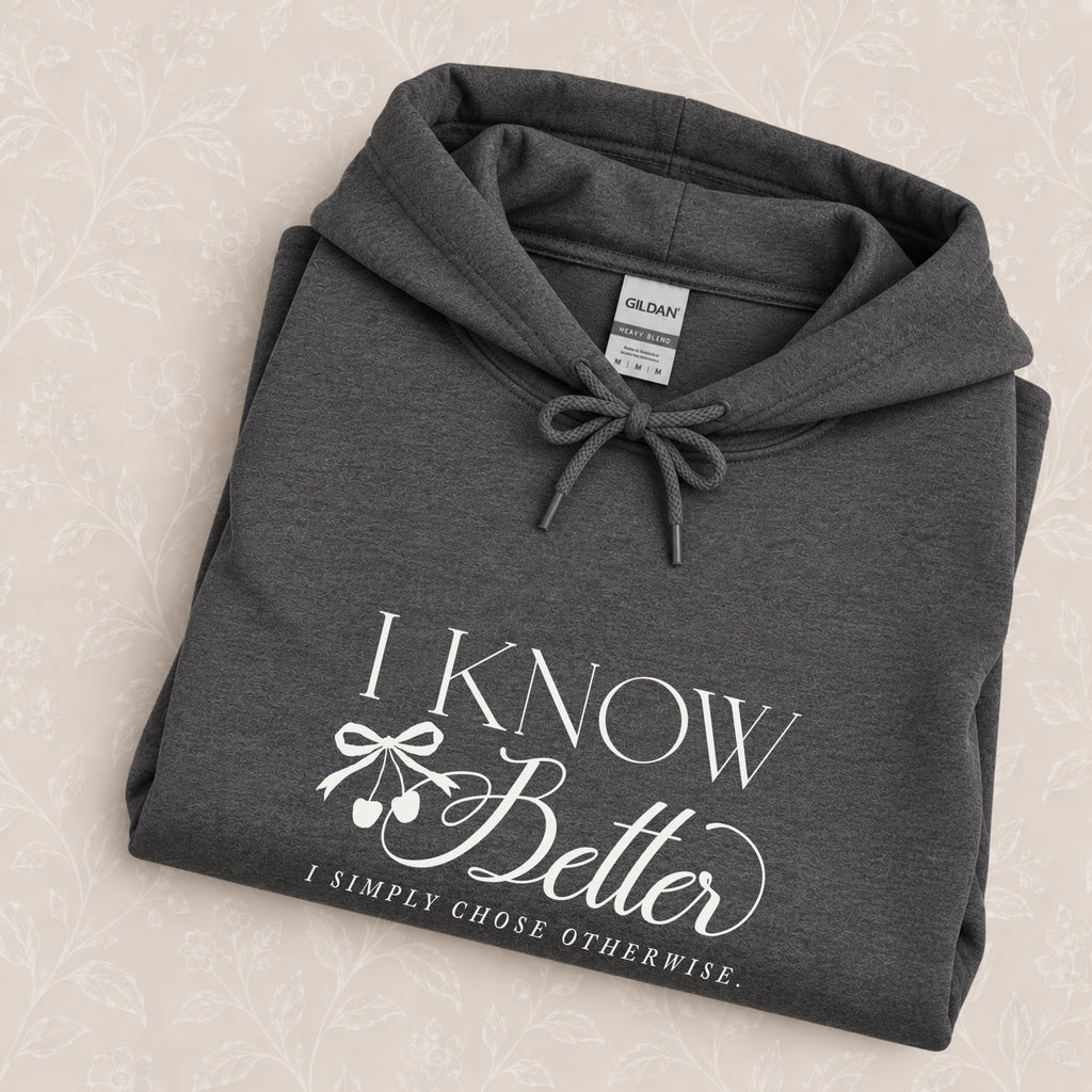 I Know Better, I Simply Chose Otherwise hoodie in Dark Heather folded on a cream floral surface, chest design close up