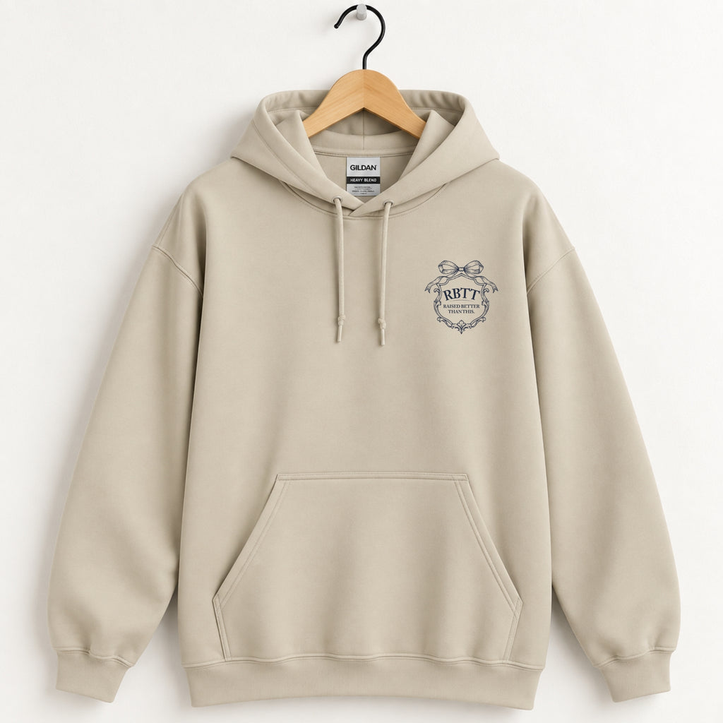 Raised Better Than This crest hoodie in Sand on a wooden hanger, navy left-chest crest