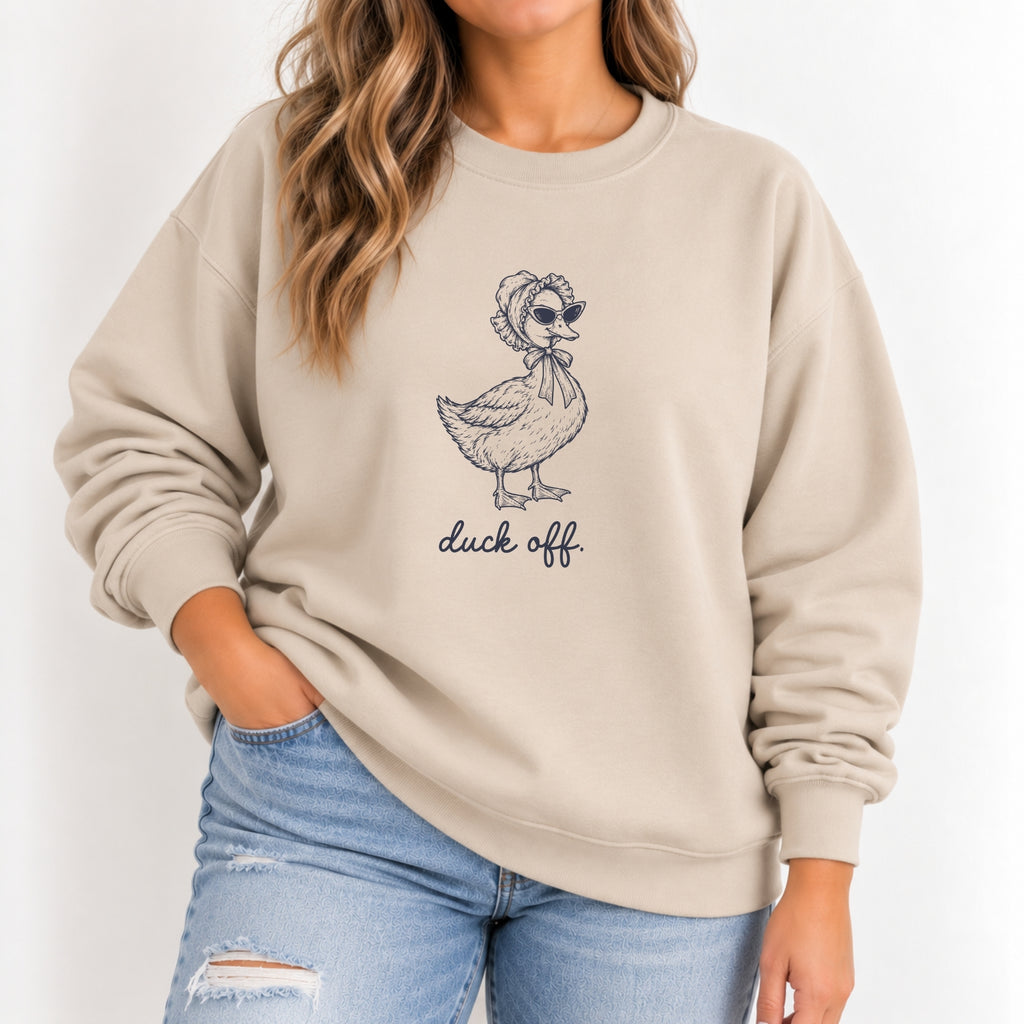 Woman wearing the Duck Off crewneck sweatshirt in Sand with jeans, navy duck design on the chest