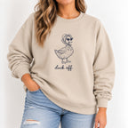 Woman wearing the Duck Off crewneck sweatshirt in Sand with jeans, navy duck design on the chest