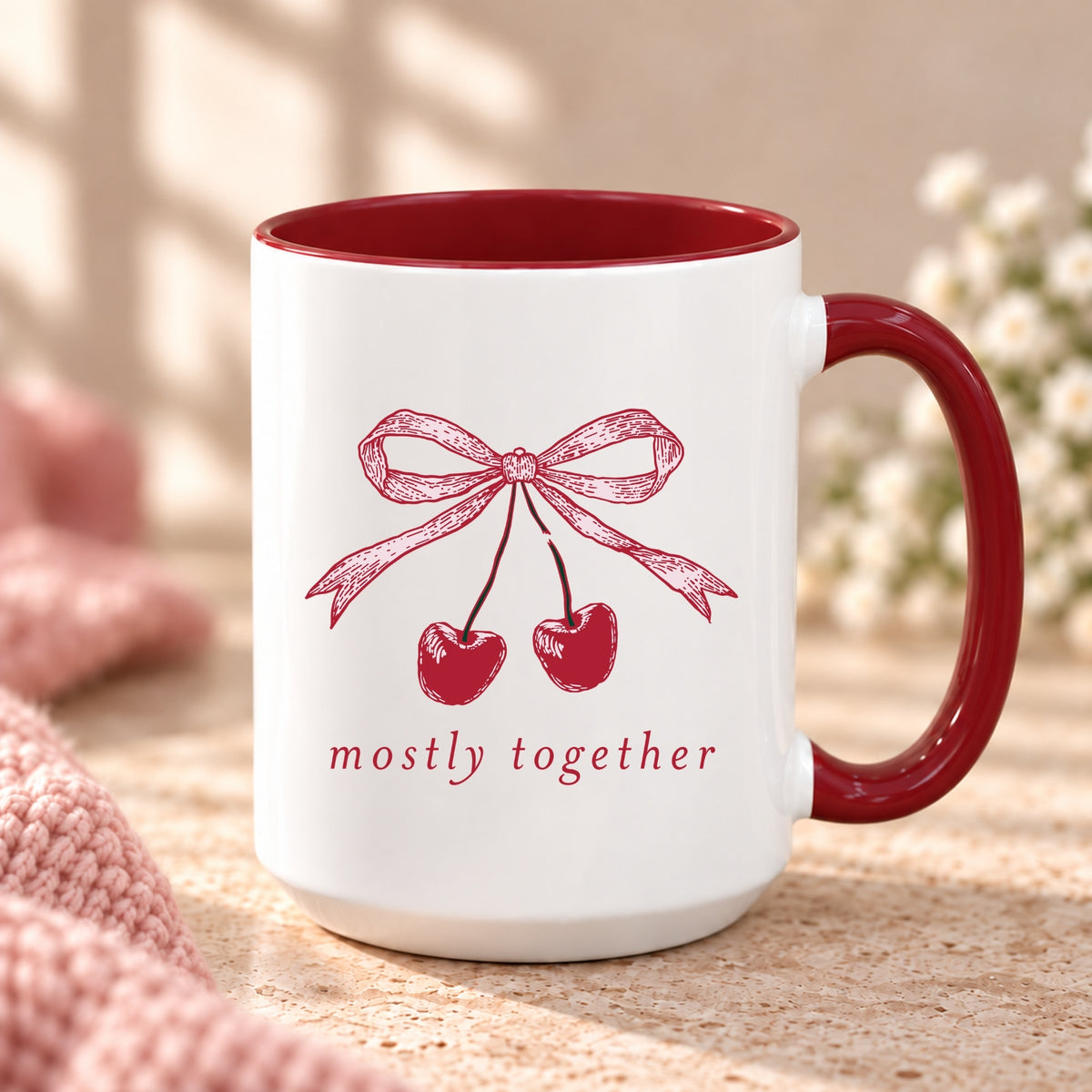 Mostly Together cherry bow mug with maroon handle and interior on a stone counter