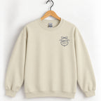 Raised Better Than This crest crewneck sweatshirt in Sand on a wooden hanger, navy left-chest crest