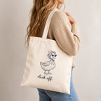 Woman in a tan sweater carrying the Duck Off canvas tote on her shoulder