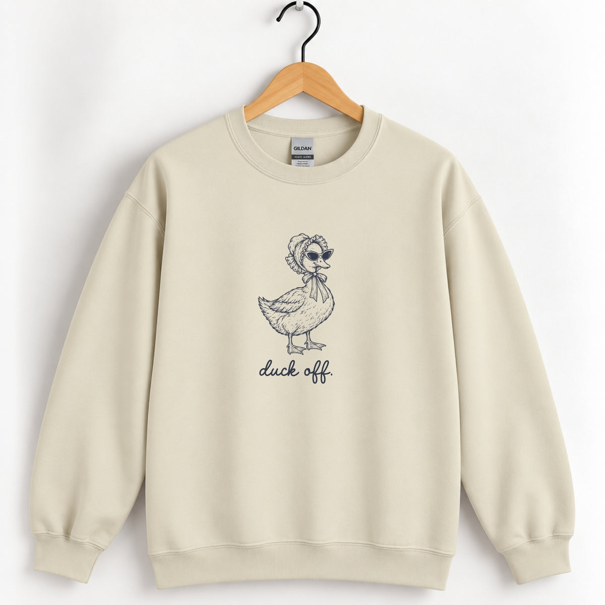 Duck Off crewneck sweatshirt in Sand on a wooden hanger, navy duck in a bonnet and sunglasses printed center chest