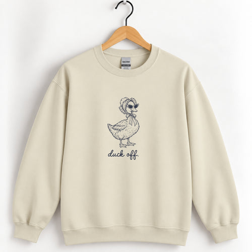 Duck Off crewneck sweatshirt in Sand on a wooden hanger, navy duck in a bonnet and sunglasses printed center chest