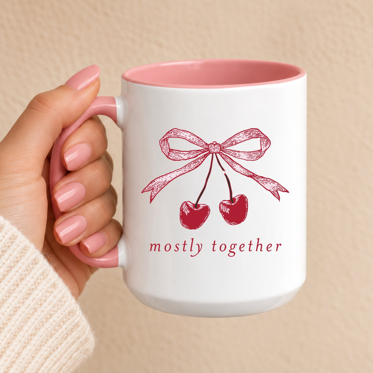 Mostly Together cherry bow mug with pink handle and interior, held in hand