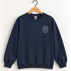 Raised Better Than This crest crewneck sweatshirt in Navy on a wooden hanger, white left-chest crest