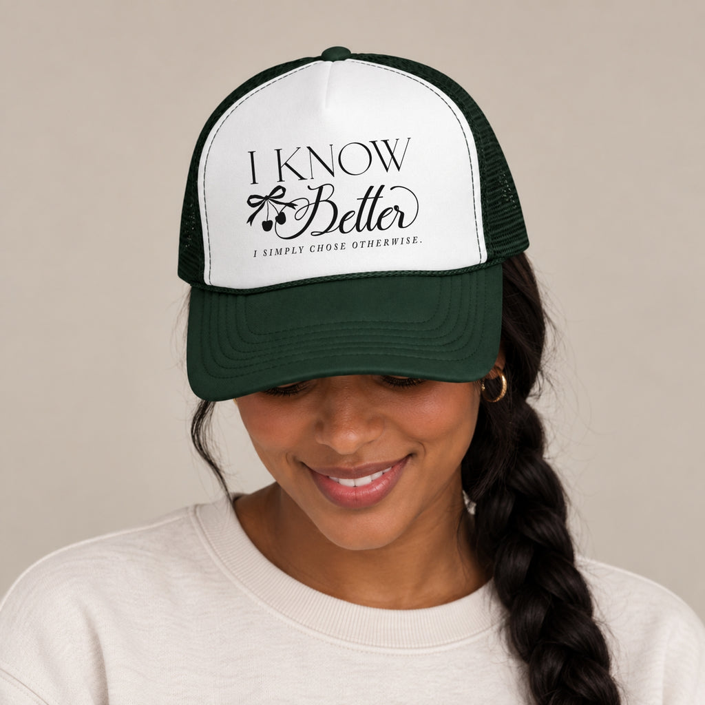 Woman with a braid wearing the I Know Better trucker hat in Dark Green