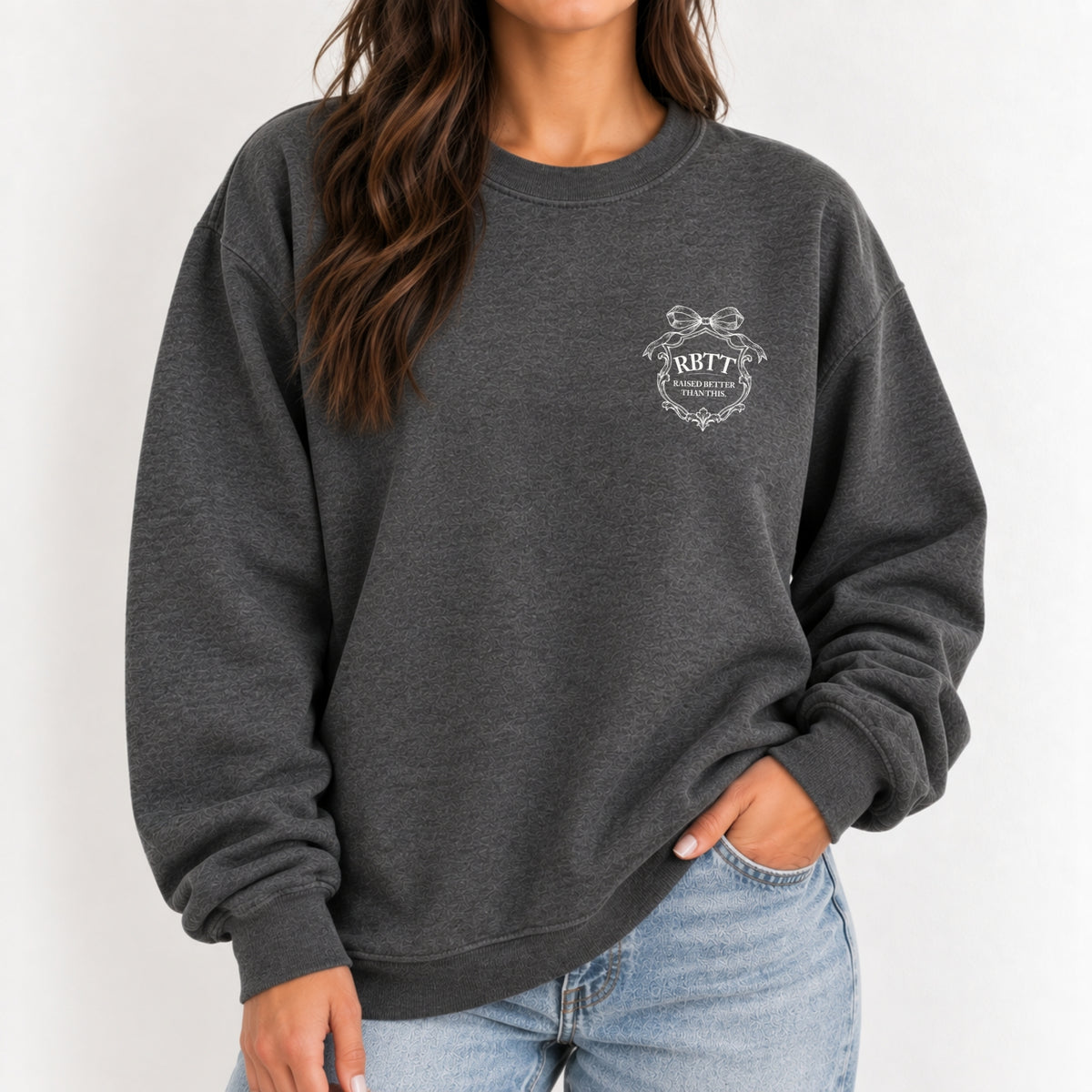 Woman wearing the Raised Better Than This crest crewneck sweatshirt in Dark Heather with jeans