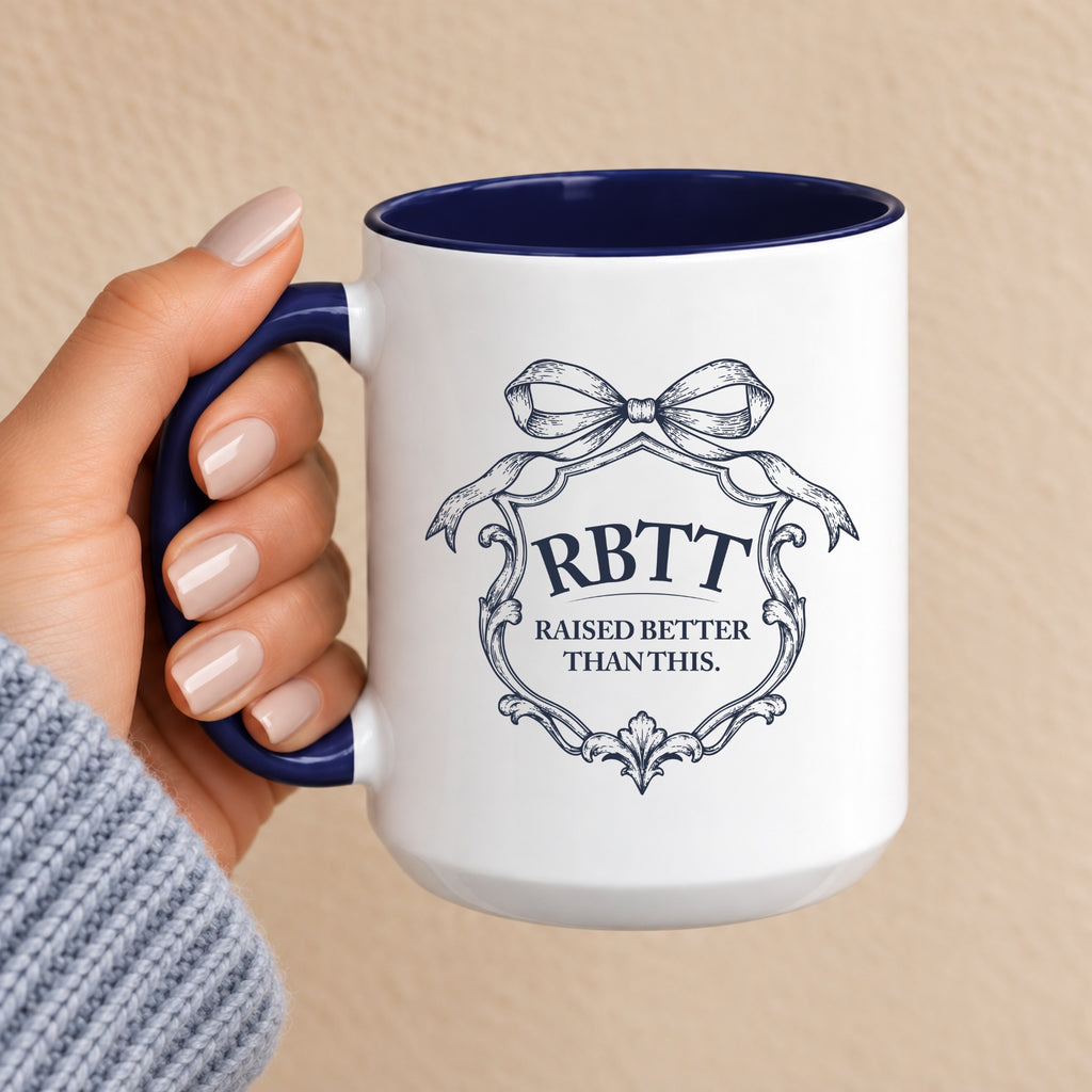 Raised Better Than This crest mug with navy handle and interior, held in hand, bow and scrollwork monogram in navy