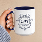 Raised Better Than This crest mug with navy handle and interior, held in hand, bow and scrollwork monogram in navy