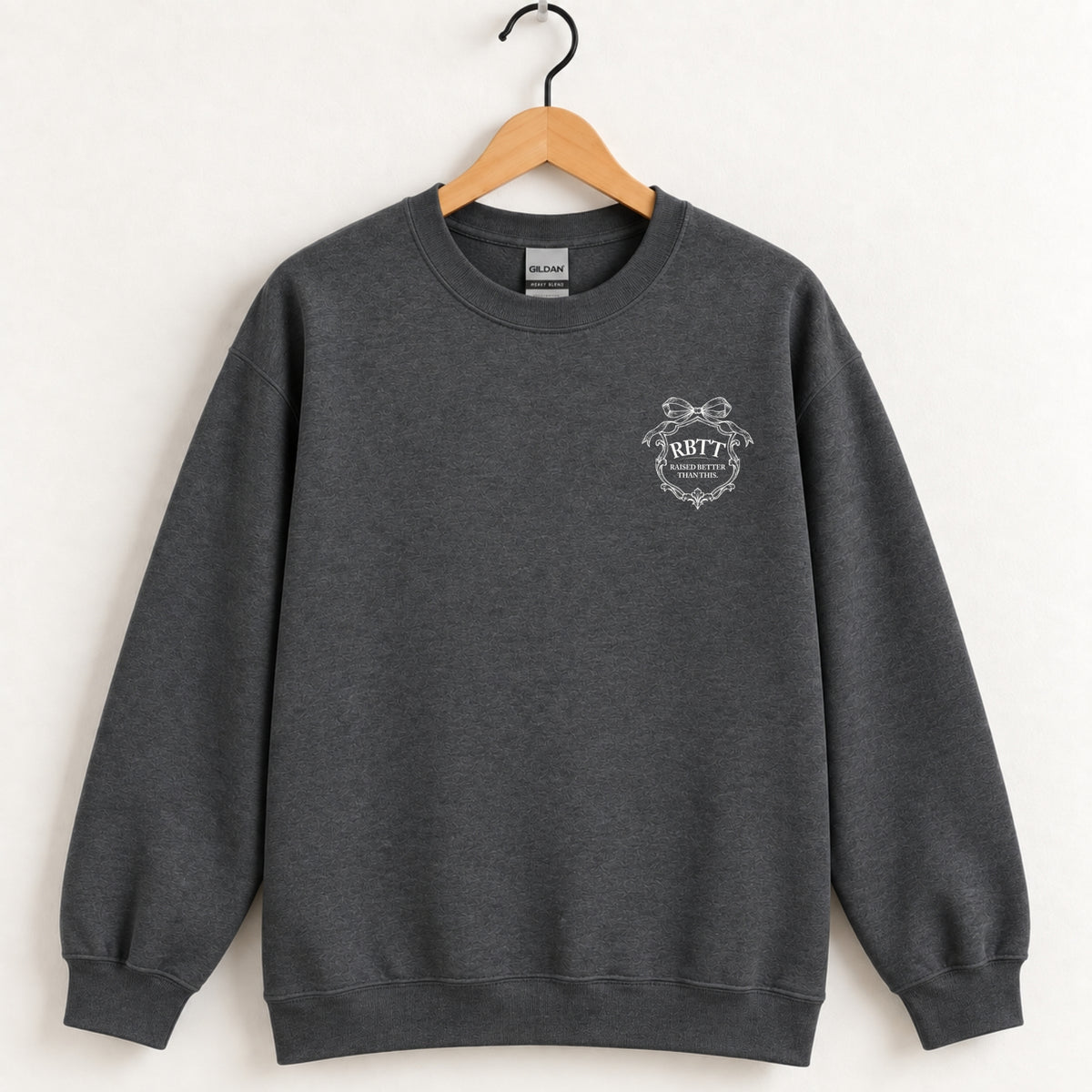 Raised Better Than This crest crewneck sweatshirt in Dark Heather on a wooden hanger
