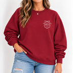 Woman wearing the Raised Better Than This crest crewneck sweatshirt in Cardinal Red with jeans