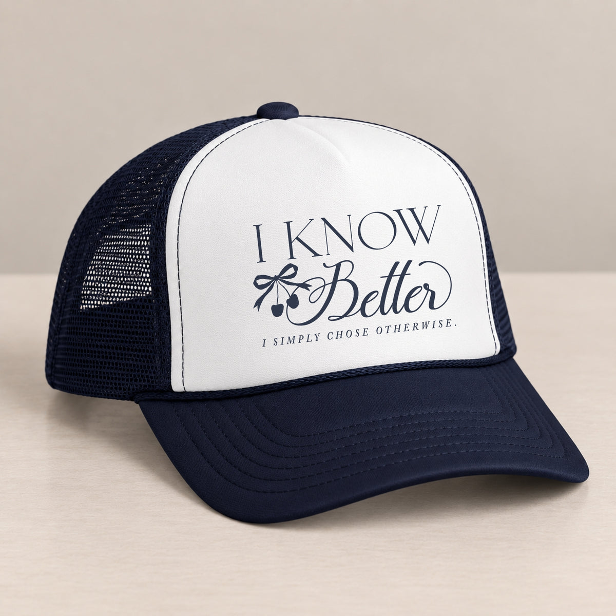 I Know Better trucker hat in Navy on a table, angled view showing the mesh back and curved bill