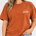 Woman wearing the Serial Reader left chest book tee in Yam (burnt orange)
