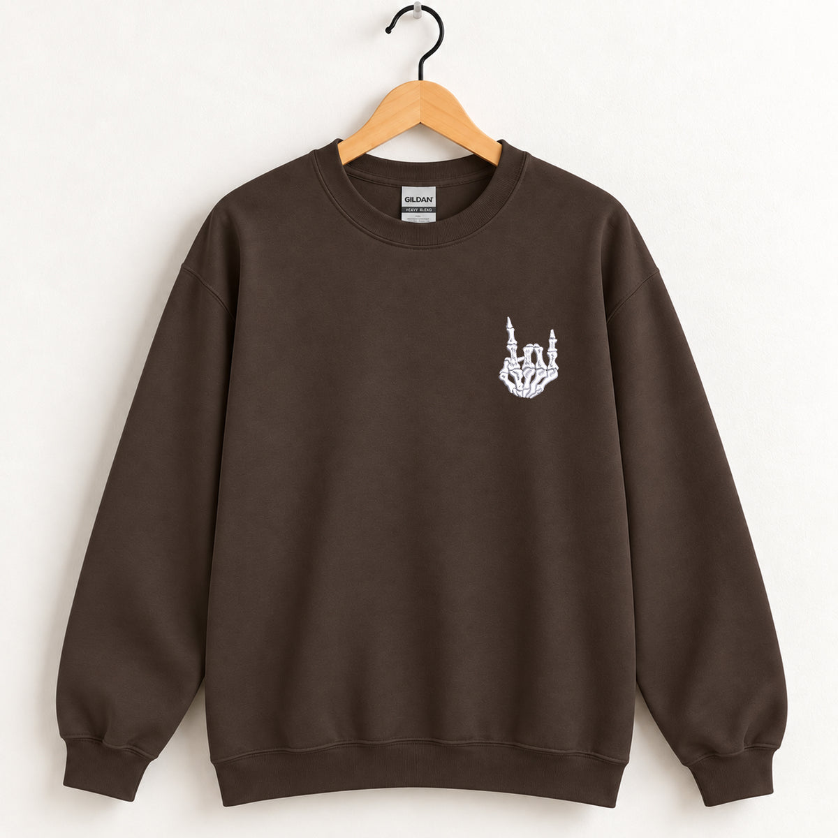 Rock On Skeleton Hand embroidered crewneck sweatshirt in Dark Chocolate on a wooden hanger