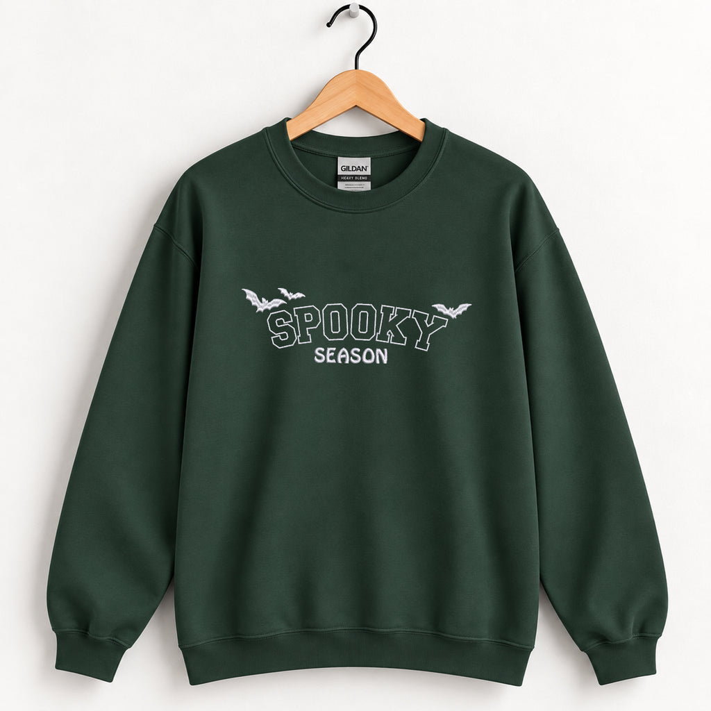 Spooky Season embroidered crewneck sweatshirt in Forest Green on a wooden hanger
