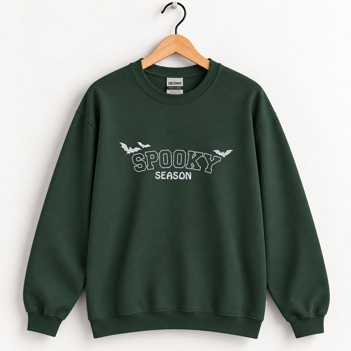 Spooky Season embroidered crewneck sweatshirt in Forest Green on a wooden hanger