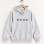Jack-o-lantern embroidered hoodie in Ash on a wooden hanger, black thread pumpkins