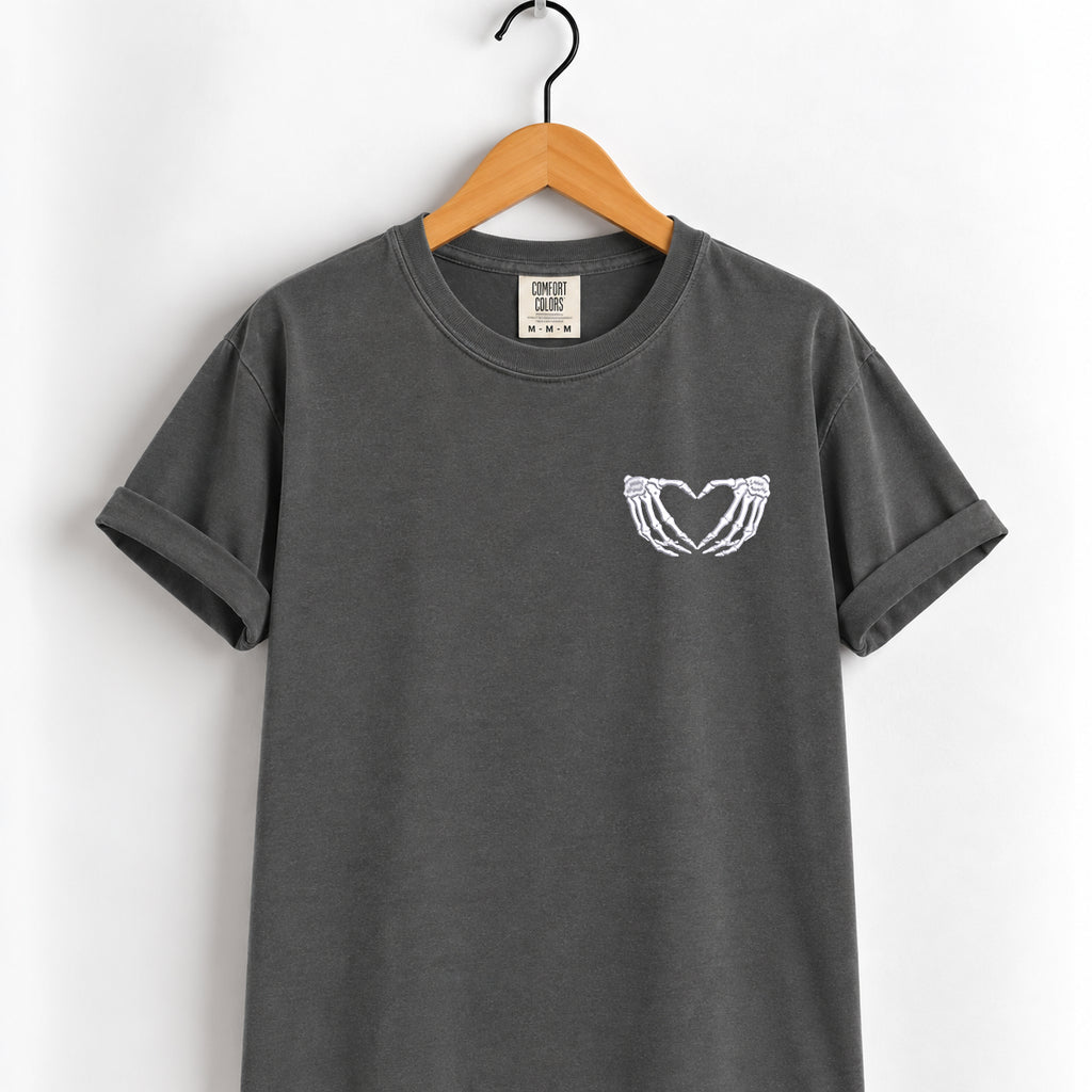 Heart hands skeleton embroidered tee in Pepper on a wooden hanger
