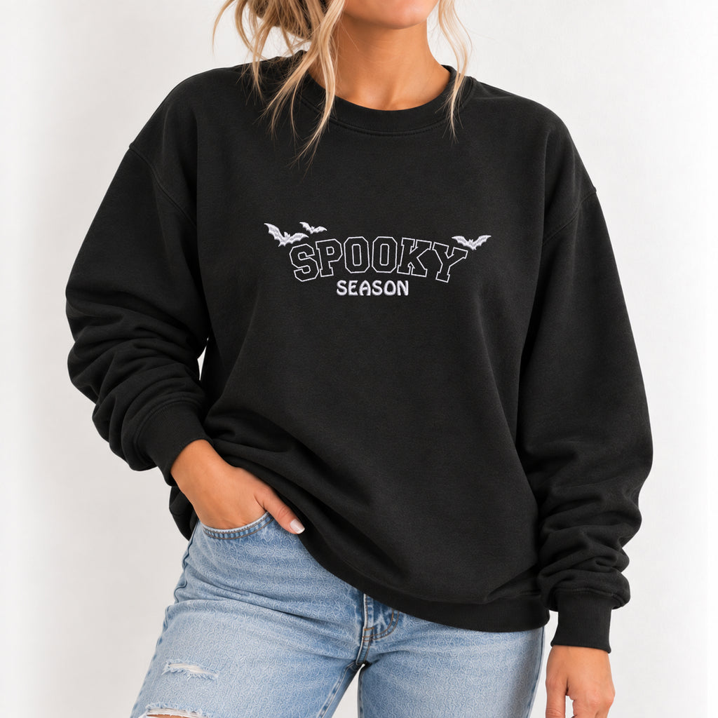 Woman wearing the Spooky Season embroidered crewneck sweatshirt in Black with jeans