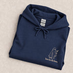 Here for the Boos hoodie in Navy folded on a cream floral surface, close up of the ivory ghost and martini print