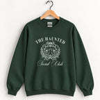 The Haunted Social Club crewneck sweatshirt in Forest Green on a wooden hanger