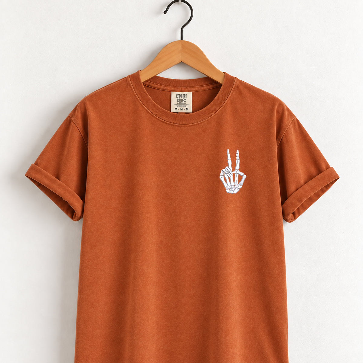 Peace sign skeleton hand embroidered tee in Yam on a wooden hanger