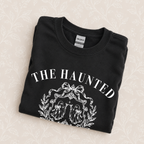 The Haunted Social Club crewneck sweatshirt in Black folded on a cream floral surface, close up of the ghost crest