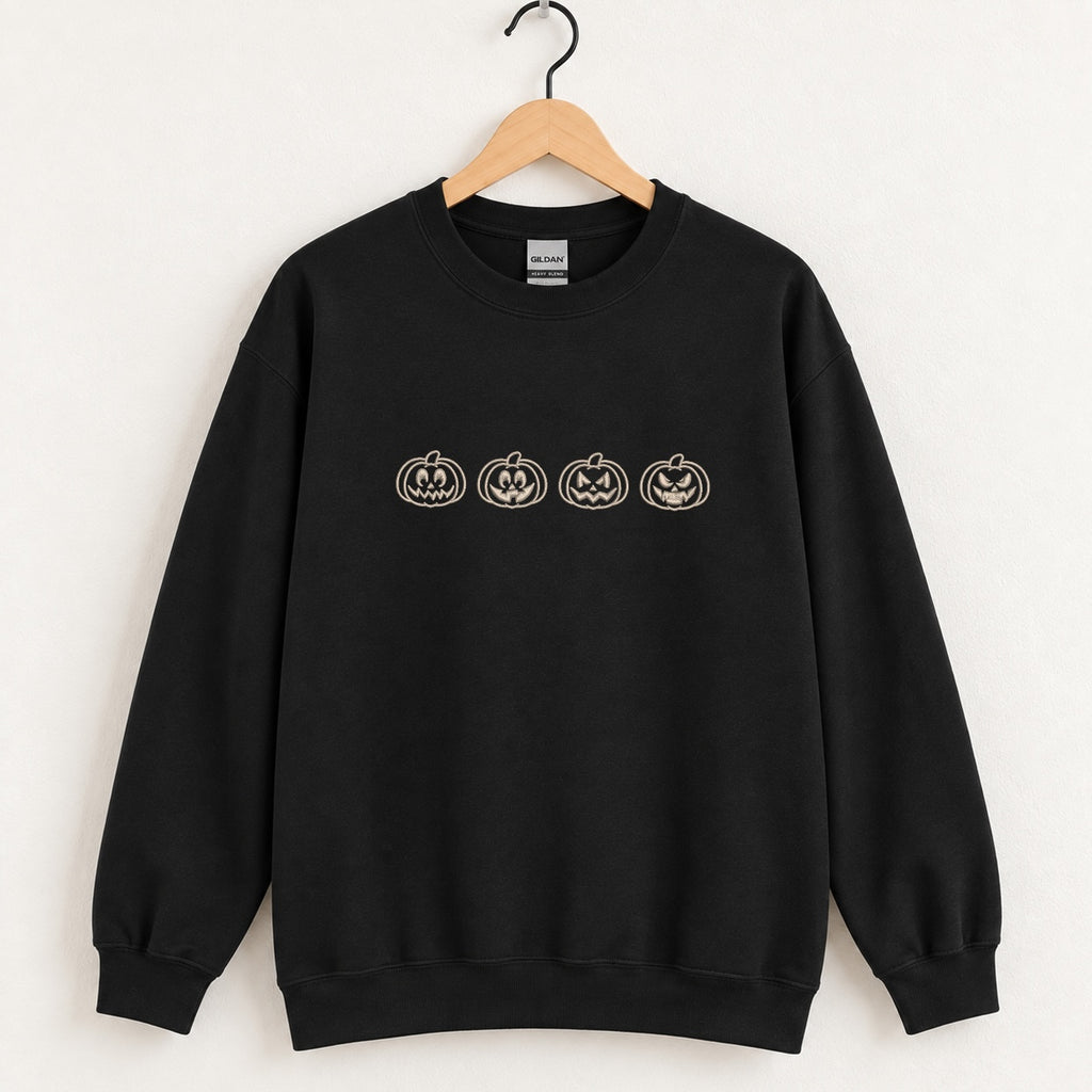 Jack-o-lantern embroidered crewneck sweatshirt in Black on a wooden hanger, four ivory pumpkins across the chest