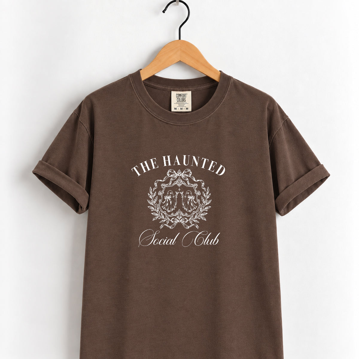 The Haunted Social Club tee in Espresso on a wooden hanger