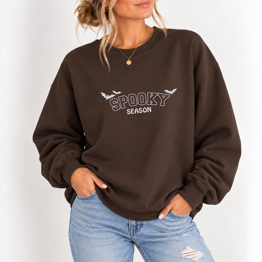 Woman wearing the Spooky Season embroidered crewneck sweatshirt in Dark Chocolate with jeans