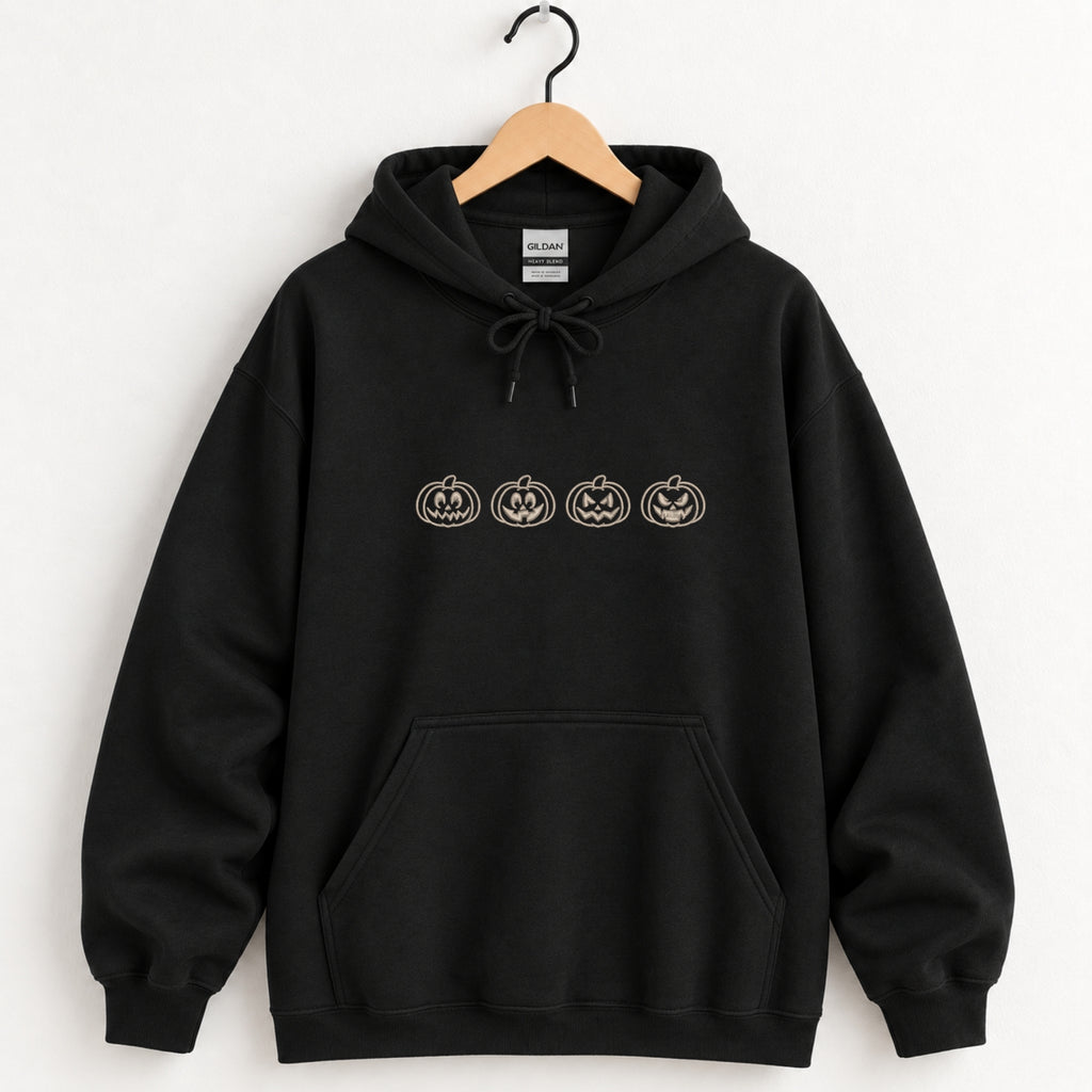 Jack-o-lantern embroidered hoodie in Black on a wooden hanger, four ivory pumpkins across the chest