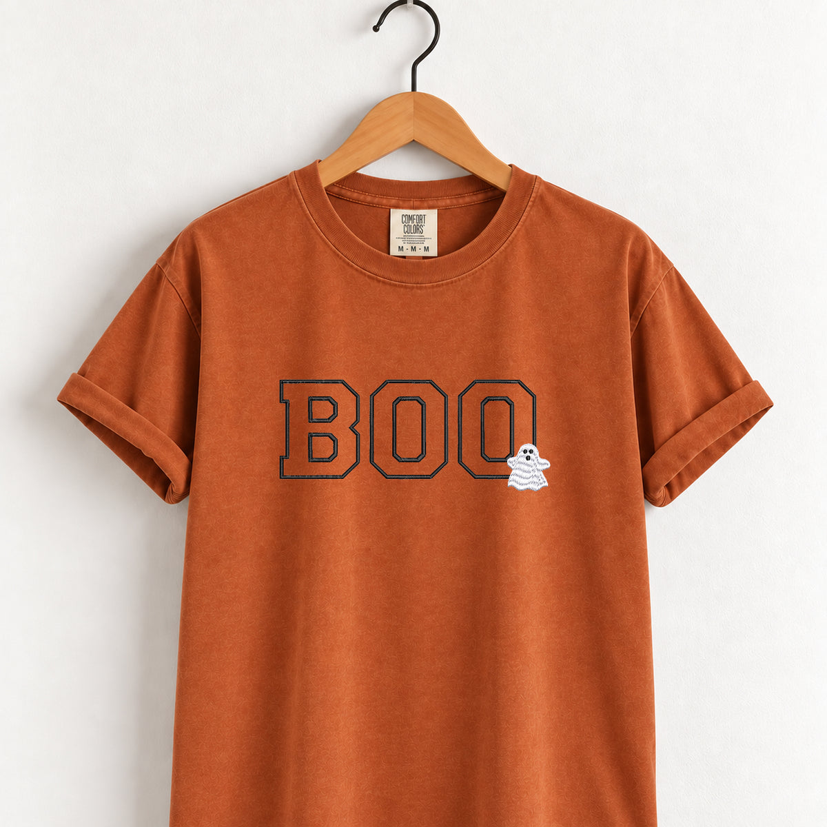 Boo embroidered tee in Yam (burnt orange) on a wooden hanger, varsity BOO outline stitching with a small ghost