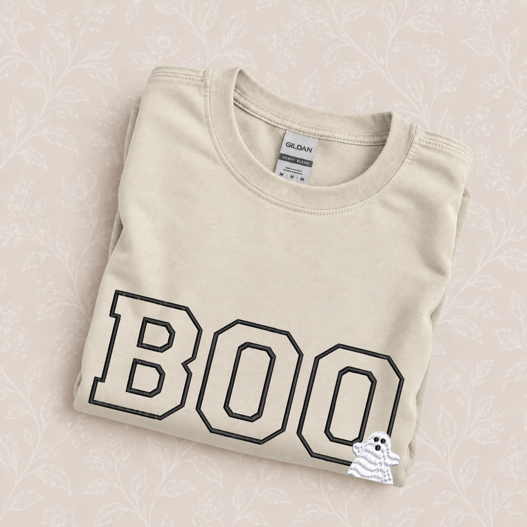 Boo embroidered crewneck sweatshirt in Sand folded on a cream floral surface, close up of the varsity BOO and ghost embroidery