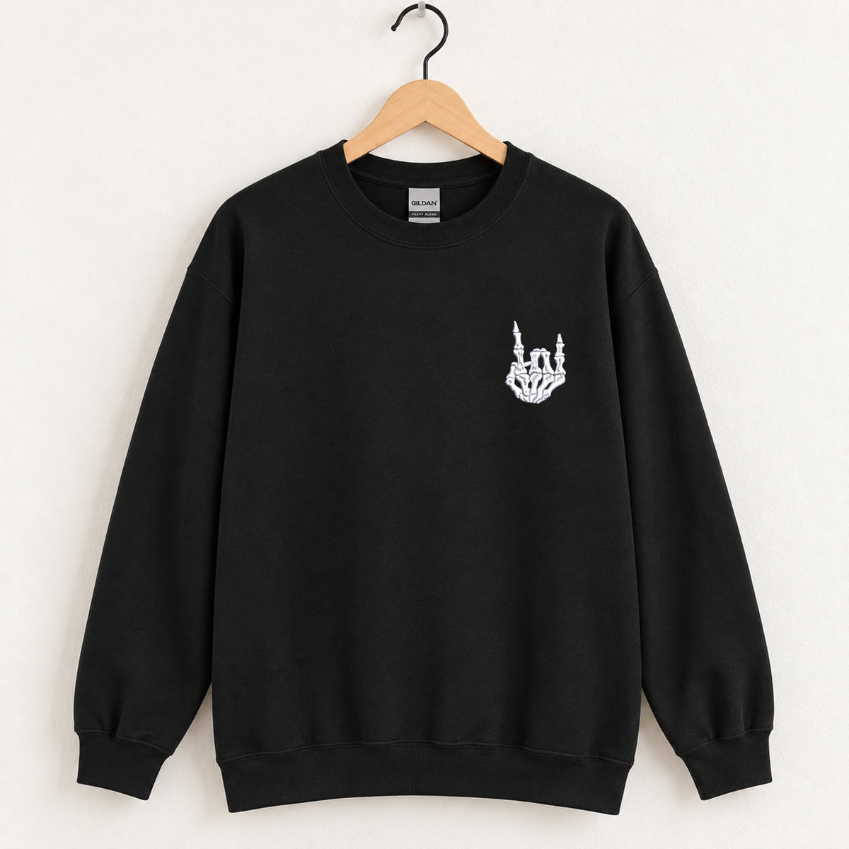 Rock On Skeleton Hand embroidered crewneck sweatshirt in Black on a wooden hanger, white thread rock-on skeleton hand on the left chest