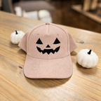 Jack-o-lantern embroidered corduroy snapback hat in Dusty Rose with a black thread pumpkin face, on a wooden table