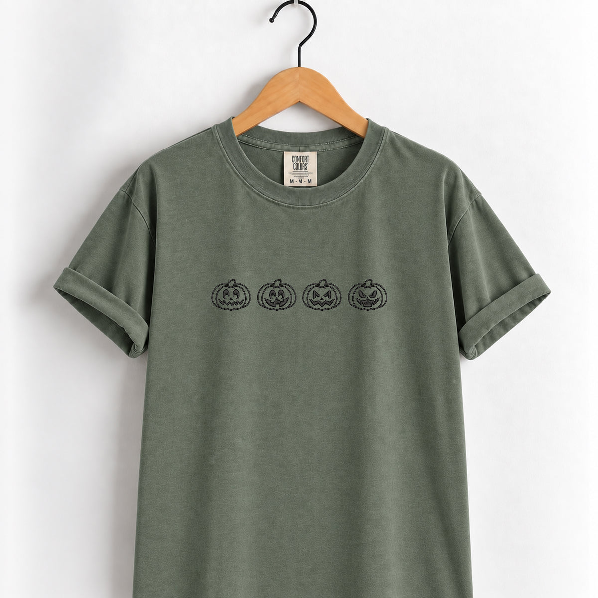 Jack-o-lantern embroidered tee in Moss on a wooden hanger