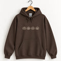 Jack-o-lantern embroidered hoodie in Dark Chocolate on a wooden hanger, ivory thread pumpkins