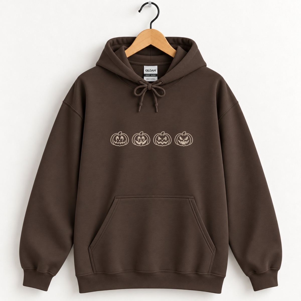 Jack-o-lantern embroidered hoodie in Dark Chocolate on a wooden hanger, ivory thread pumpkins