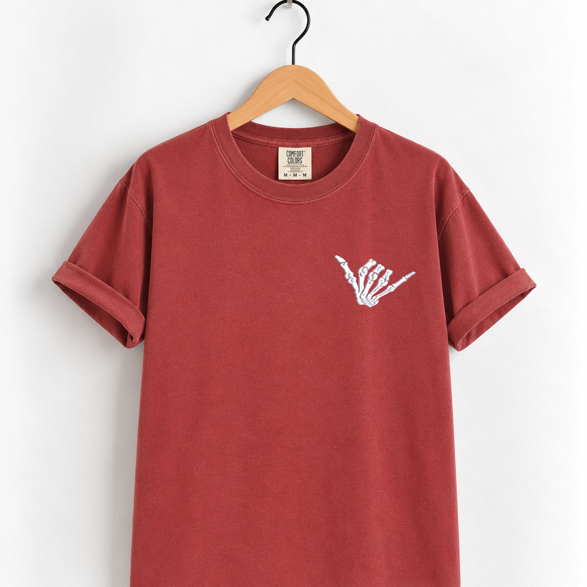 Shaka skeleton hand embroidered tee in Chili on a wooden hanger