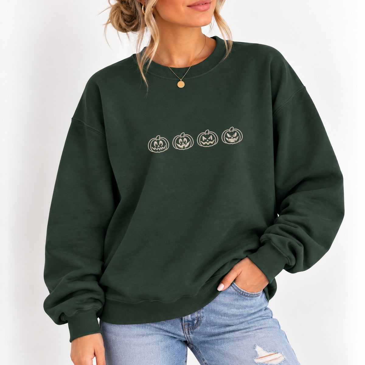 Woman wearing the jack-o-lantern embroidered crewneck sweatshirt in Forest Green with jeans
