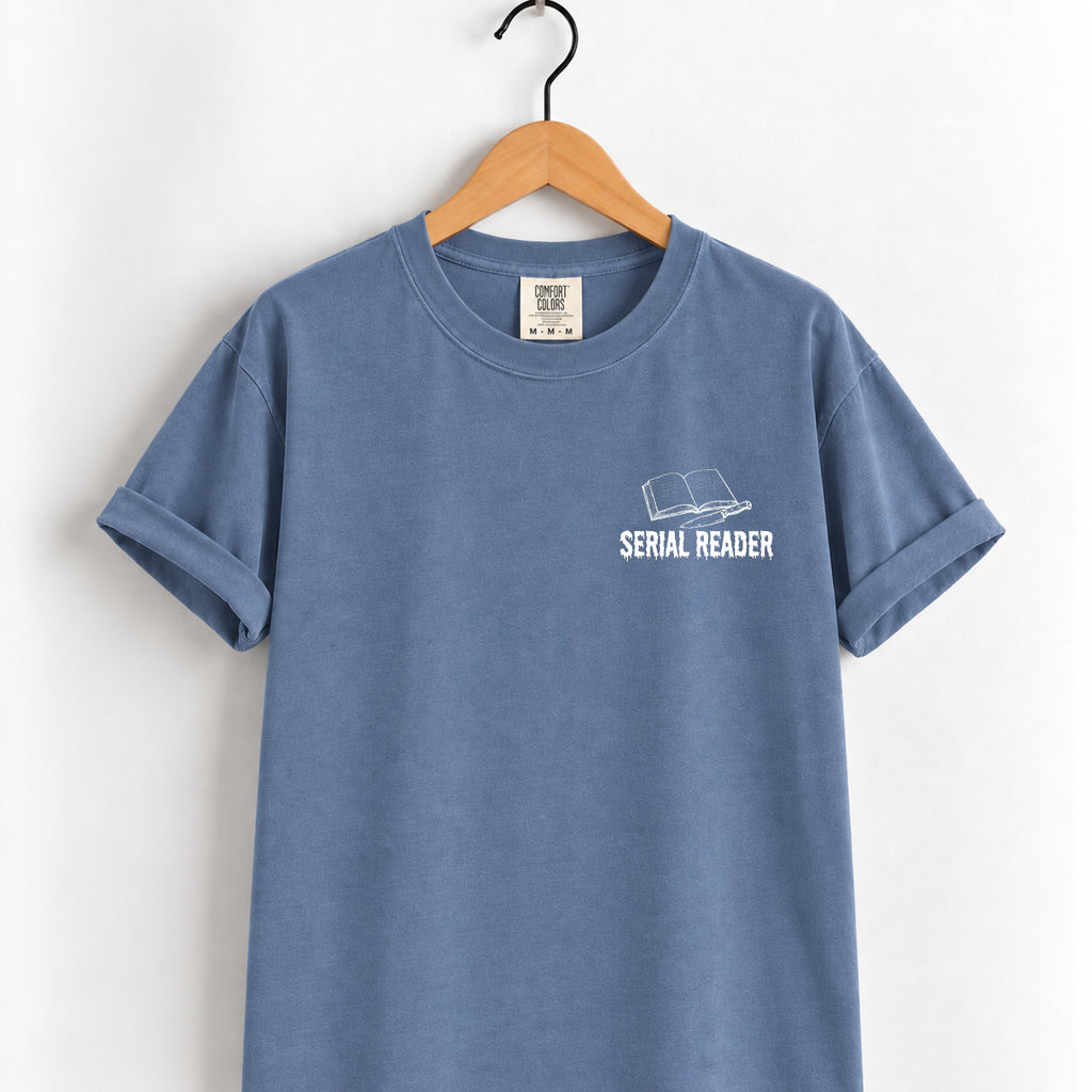 Serial Reader tee in Blue Jean on a wooden hanger, small white open-book left chest print