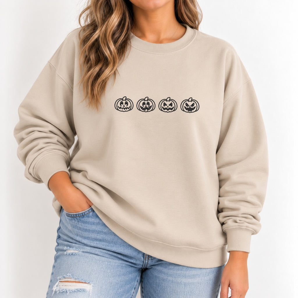 Woman wearing the jack-o-lantern embroidered crewneck sweatshirt in Sand with jeans, black thread pumpkins