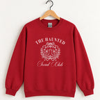 The Haunted Social Club crewneck sweatshirt in Cardinal Red on a wooden hanger